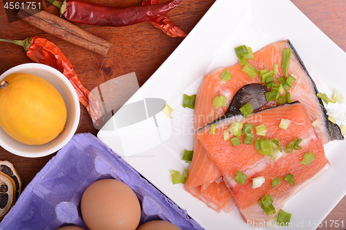 Image of fresh salmon fillet on white plate. red pepper, cinnamon and lemon