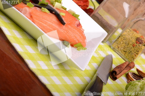 Image of fresh salmon fillet on white plate. knife, red pepper, cinnamon and lemon