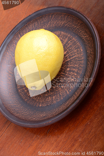 Image of Lemons in a brown bowl on a wooden background