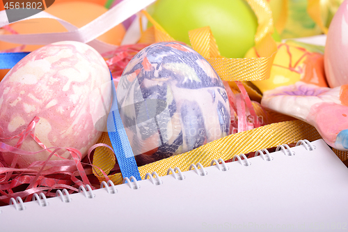 Image of Handcrafted easter eggs close up, white notepad, ribbons and decoration