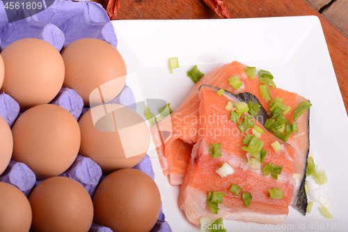 Image of fresh salmon fillet close up on white plate. red pepper, eggs and lemon