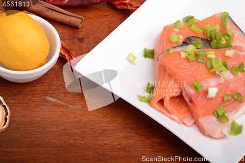 Image of fresh salmon fillet on white plate. red pepper, cinnamon and lemon