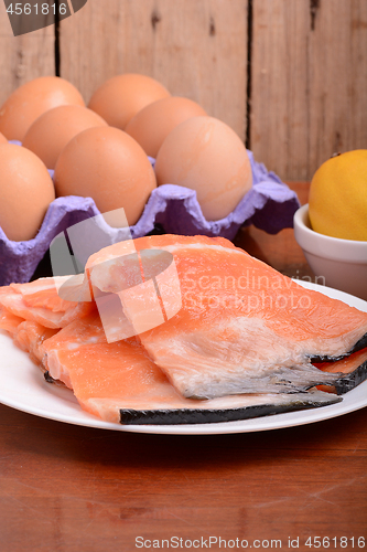 Image of fresh salmon fillet close up on white plate. eggs and lemon