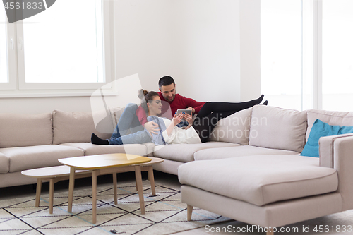 Image of couple relaxing at  home with tablet computers