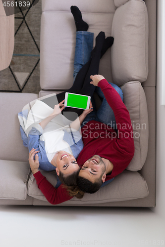 Image of couple relaxing at  home with tablet computers