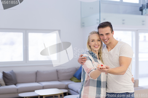 Image of couple showing small red house in hands