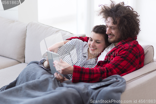 Image of couple relaxing at  home with tablet computers