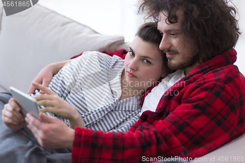 Image of couple relaxing at  home with tablet computers