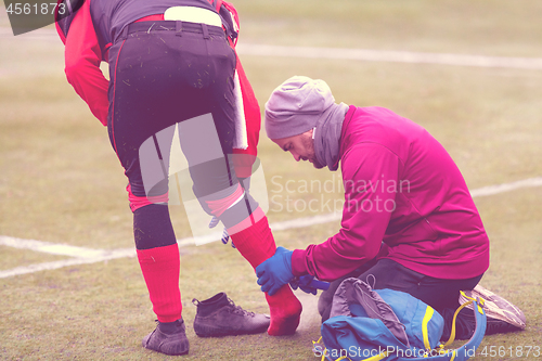 Image of Sports doctor using freezing spray while treating injured sportm