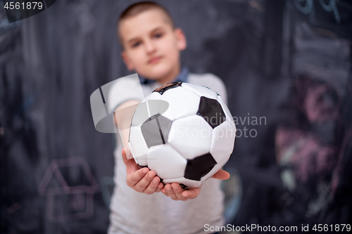 Image of happy boy holding a soccer ball in front of chalkboard