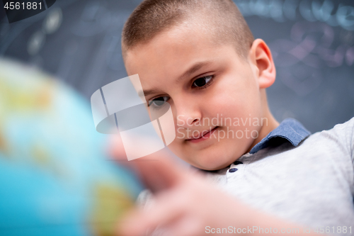 Image of boy using globe of earth in front of chalkboard