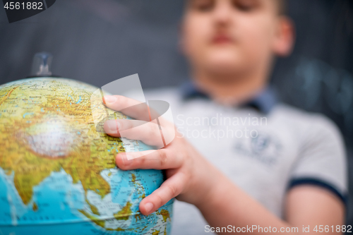 Image of boy using globe of earth in front of chalkboard