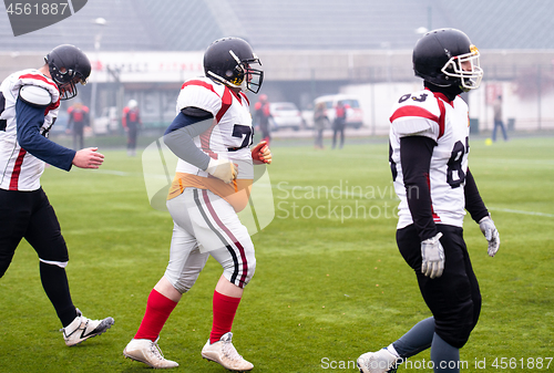 Image of confident American football players leaving the field