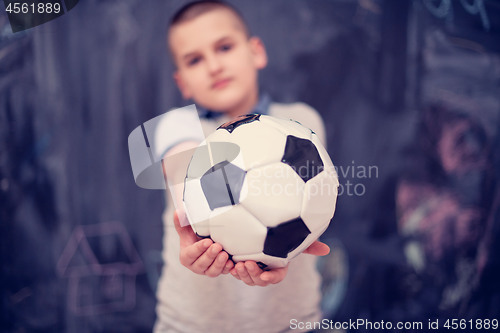 Image of happy boy holding a soccer ball in front of chalkboard