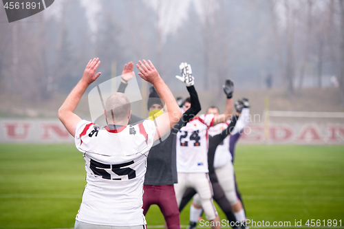 Image of american football players stretching and warming up