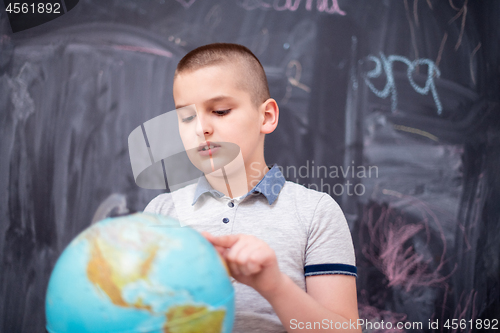 Image of boy using globe of earth in front of chalkboard