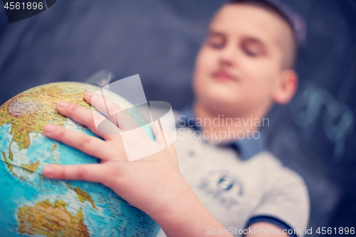 Image of boy using globe of earth in front of chalkboard
