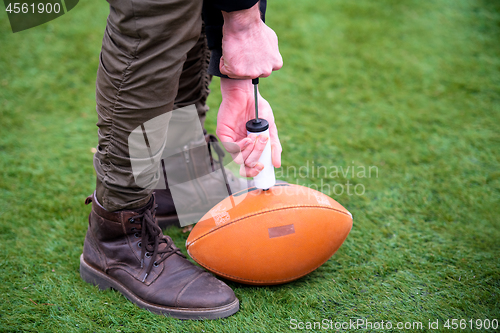 Image of man pumping air into american football ball