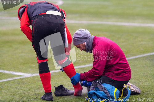 Image of Sports doctor using freezing spray while treating injured sportm