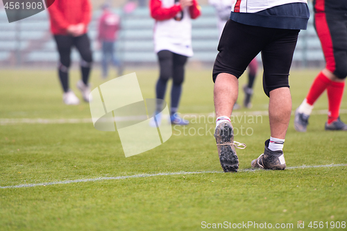 Image of close up of american football players stretching and warming up