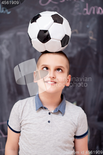 Image of happy boy holding a soccer ball on his head