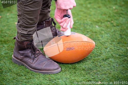 Image of man pumping air into american football ball