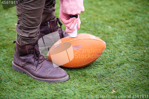 Image of man pumping air into american football ball