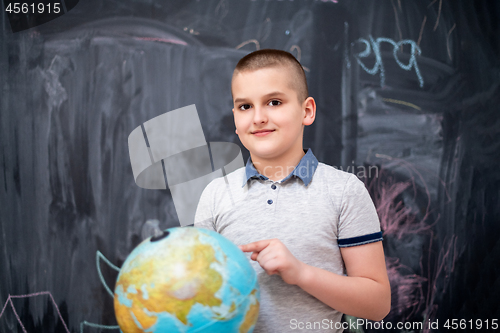 Image of boy using globe of earth in front of chalkboard