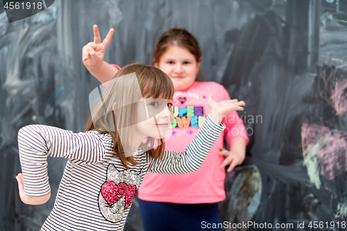 Image of little girls having fun in front of chalkboard