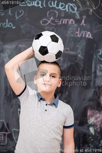 Image of happy boy holding a soccer ball on his head