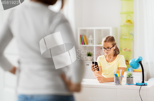 Image of girl listening to music and mother entering room