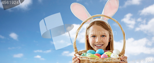 Image of happy girl with easter eggs in basket over sky