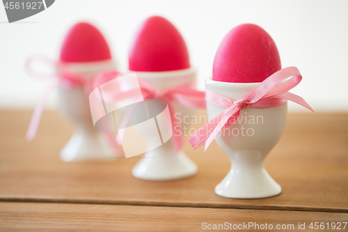 Image of pink colored easter eggs in holders on table