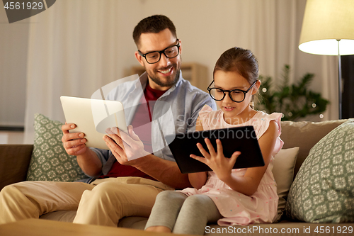 Image of father and daughter with tablet computers at home