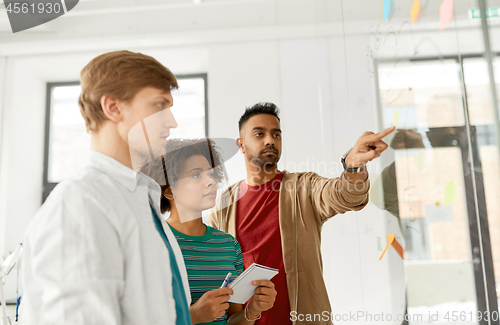 Image of creative team looking at office glass board