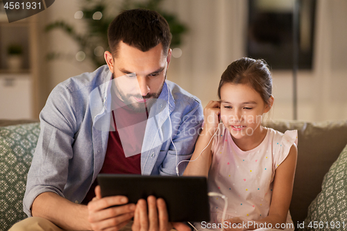 Image of father and daughter listening to music on tablet