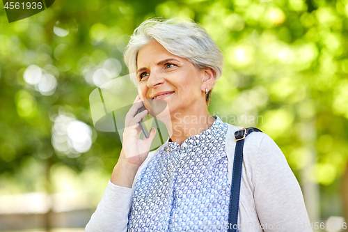 Image of senior woman calling on smartphone in summer park