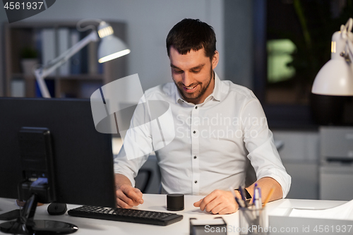 Image of businessman using smart speaker at night office