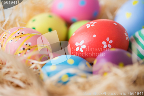 Image of close up of colored easter eggs in straw