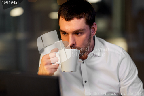 Image of businessman drinking coffee at night office