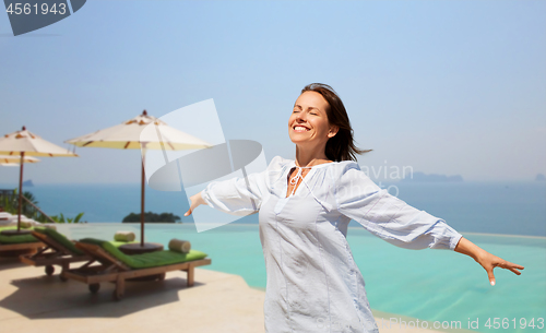 Image of happy woman enjoying sun over infinity edge pool