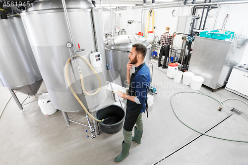 Image of man with clipboard at craft brewery or beer plant