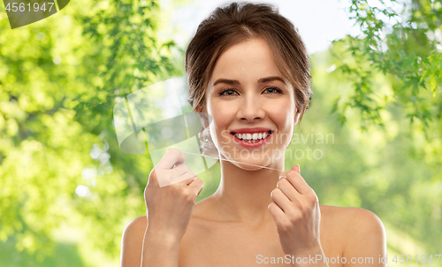 Image of happy young woman with dental floss cleaning teeth