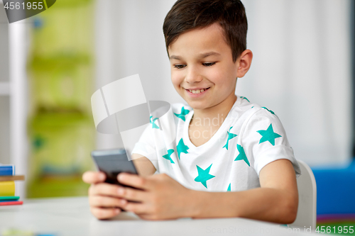 Image of happy boy with smartphone at home