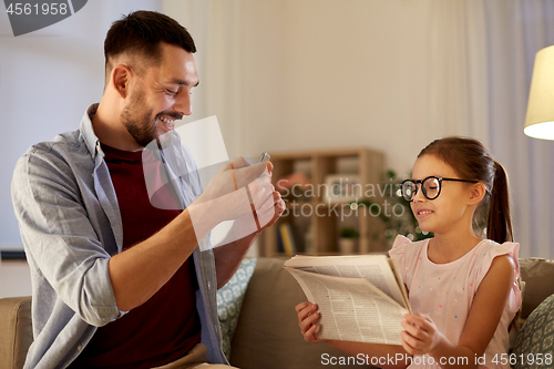 Image of father photographing daughter by cellphone at home