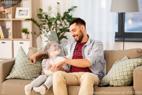 Image of happy father and daughter eating popcorn at home