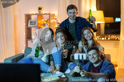 Image of friends taking picture by selfie stick at home