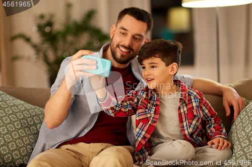 Image of father and son taking selfie at home