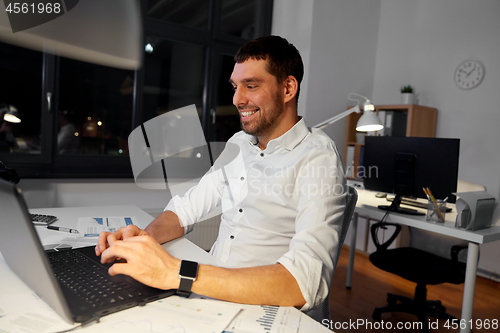 Image of businessman with laptop working at night office