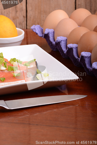 Image of fresh salmon fillet close up on white plate. knife, eggs and lemon